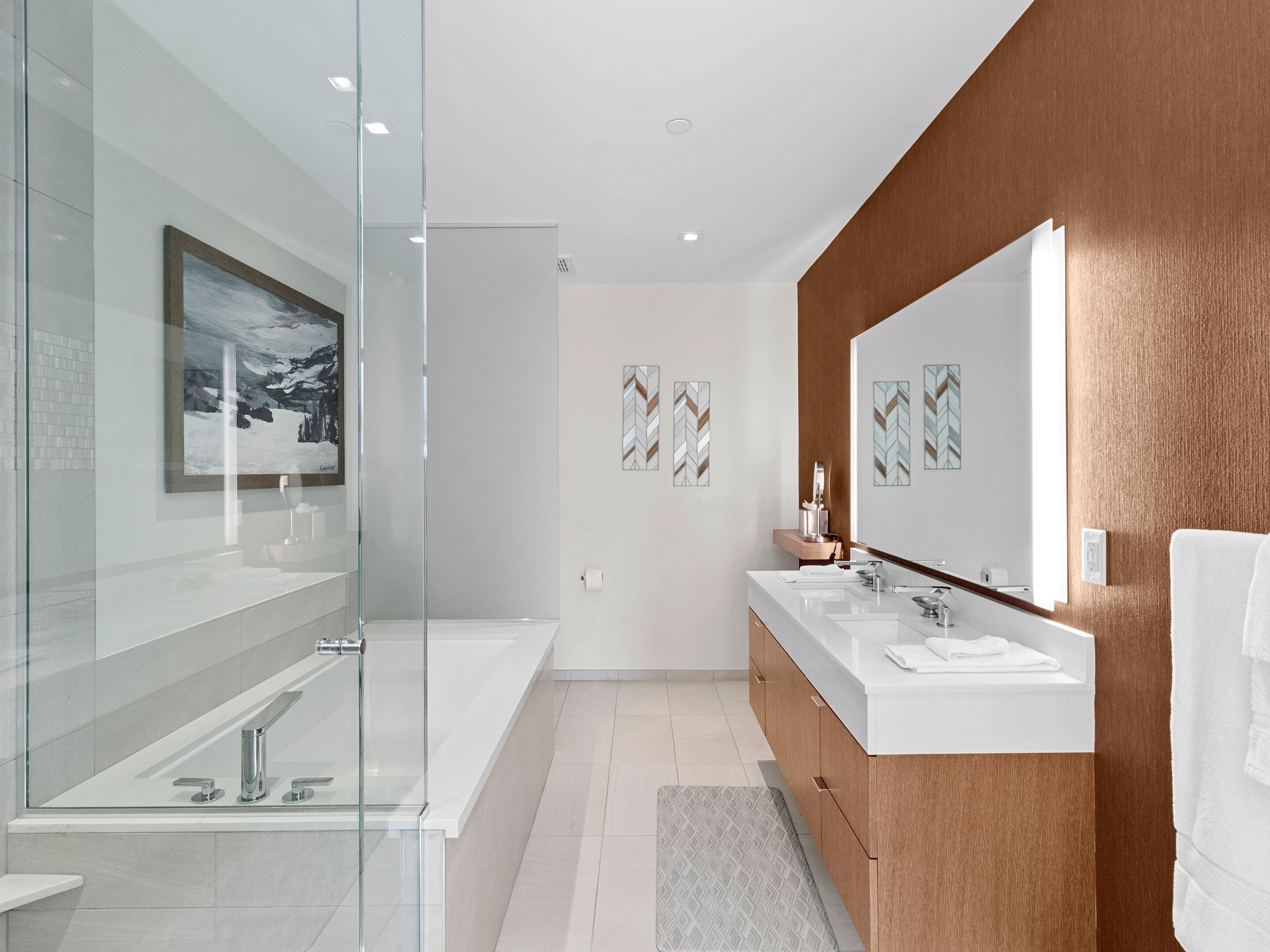 A modern bathroom with a glass shower enclosure, a large mirror, and a wooden vanity with two sinks.