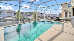 A covered outdoor swimming pool with lounge chairs, a view of residential buildings, and a clear sky. - Delight Kangaroo Home by All Vacation (Davenport)