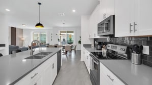 A modern kitchen with white cabinets, a black stove, and stainless steel appliances. - Delight Kangaroo Home by All Vacation (Davenport)