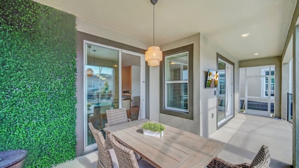 A dining area with a wooden table and wicker chairs, a hanging light fixture, and a green wall. - Delight Kangaroo Home by All Vacation (Davenport)