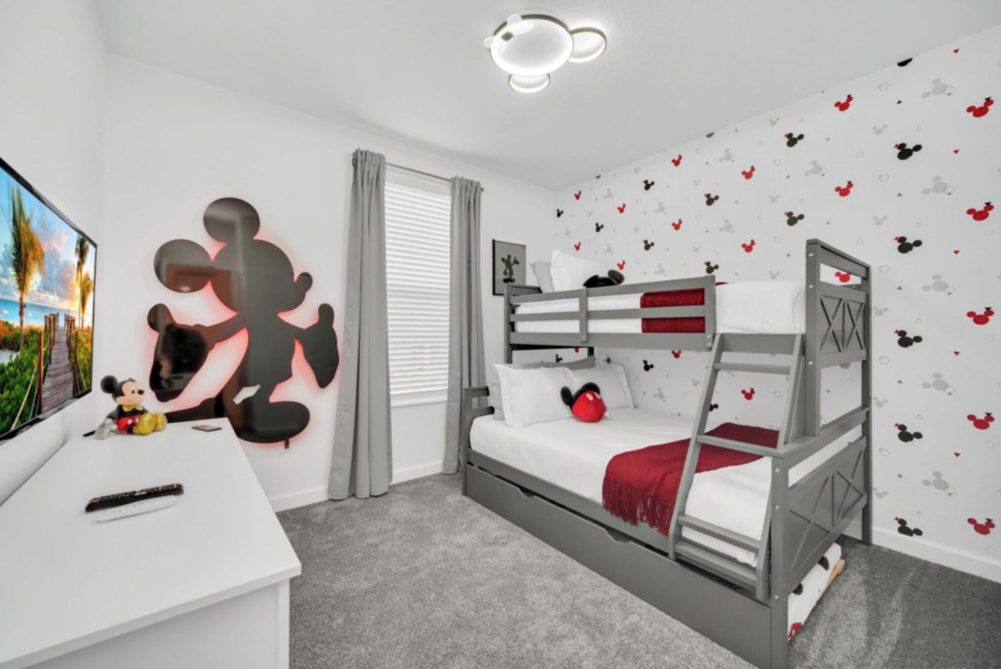 A child's bedroom with a bunk bed, a desk with a Mickey Mouse cutout, and a wall with Mickey Mouse decals.
