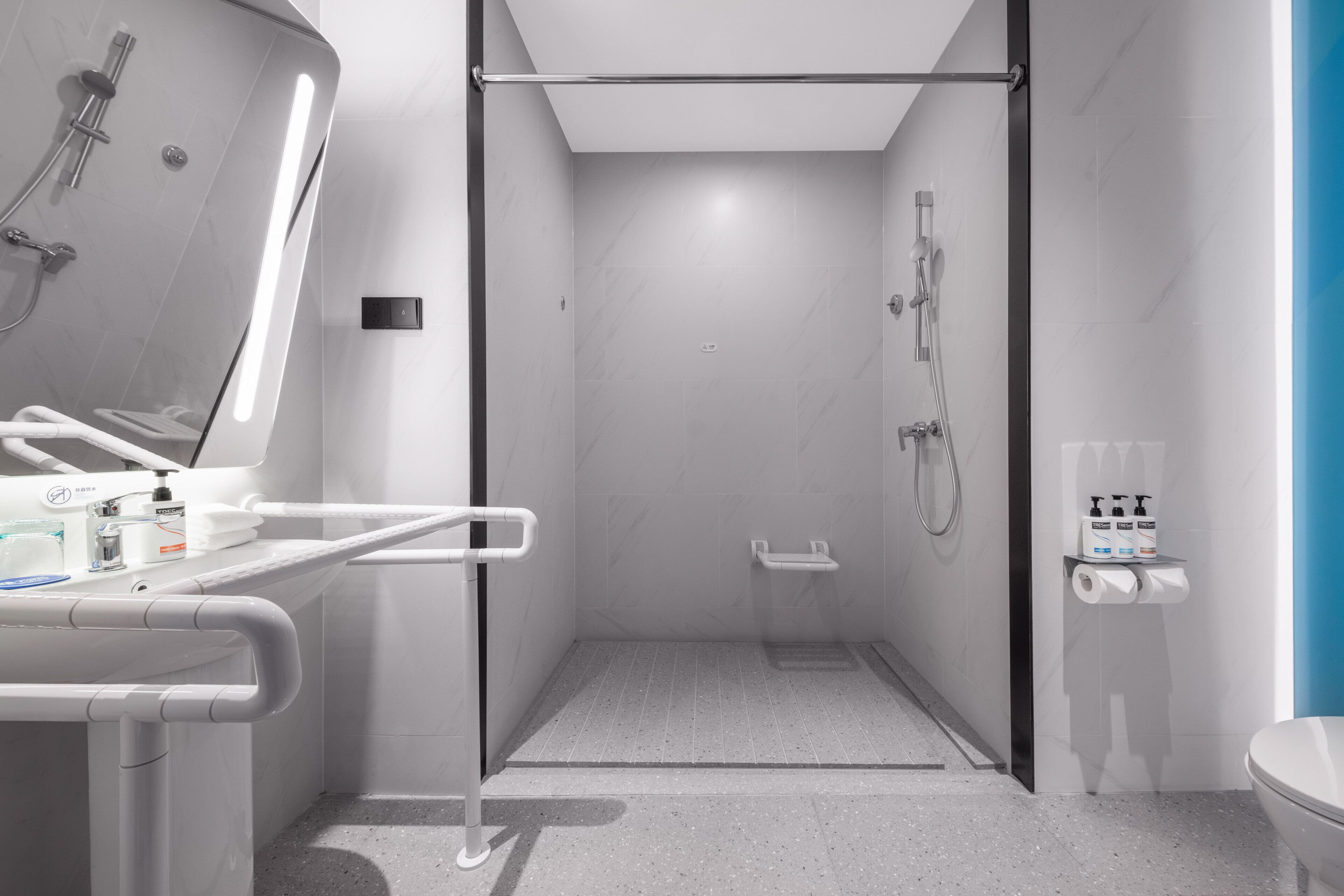 A modern bathroom with a glass-enclosed shower, a toilet, and a sink with a mirror.
