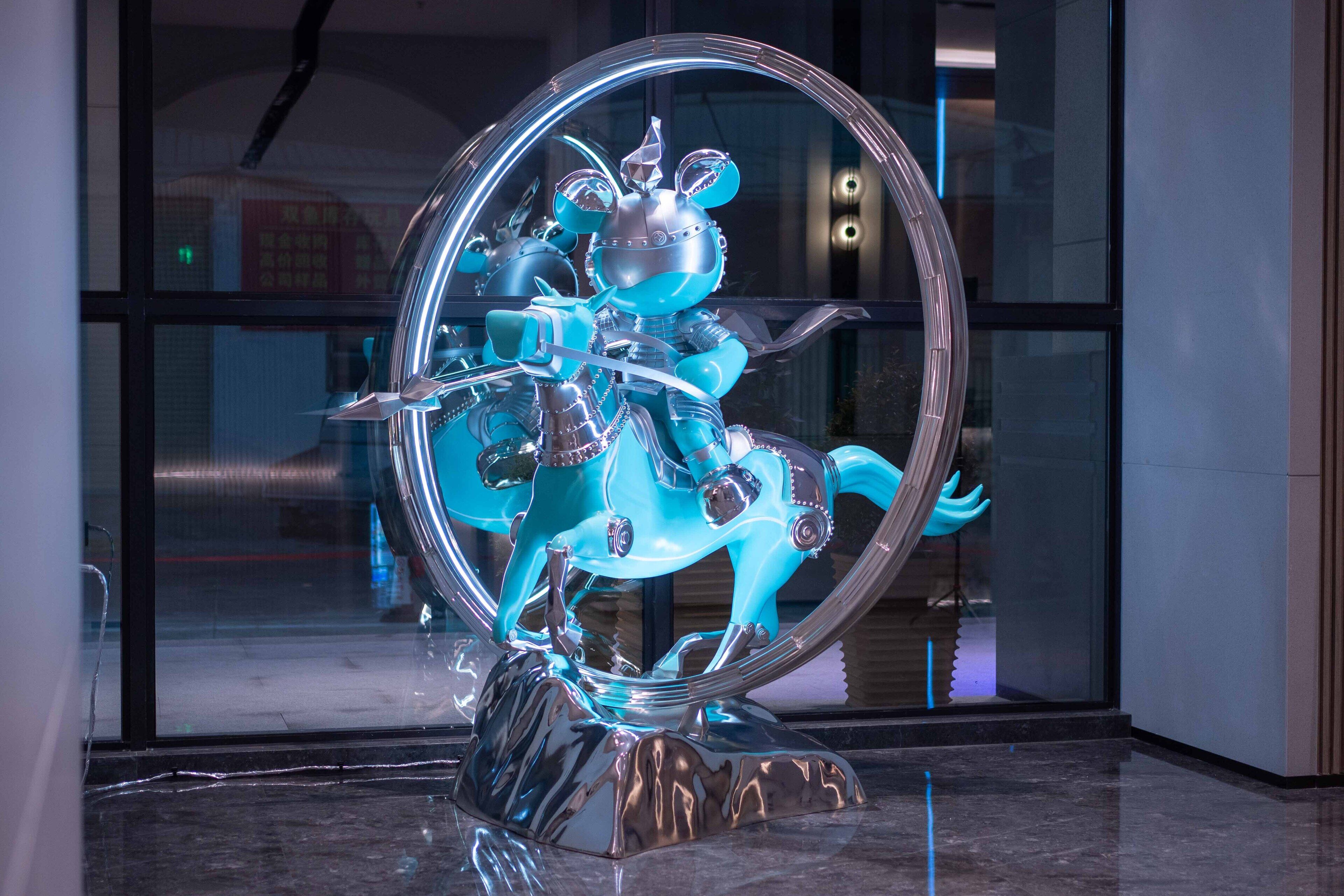 A blue horse sculpture inside a circular frame, placed on a reflective base.