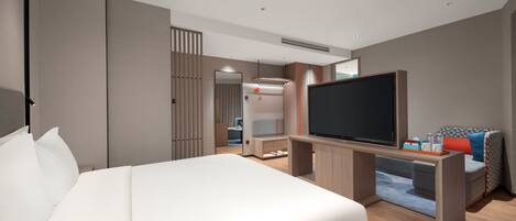 Ein modernes Hotelzimmer mit einem großen Bett, einem Flachbildfernseher, einem Schreibtisch mit Computer und einer Sitzecke mit Sofa und Sesseln.