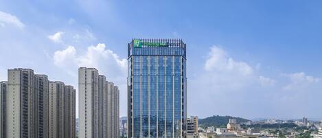 A modern high-rise hotel with a glass facade, surrounded by other buildings.