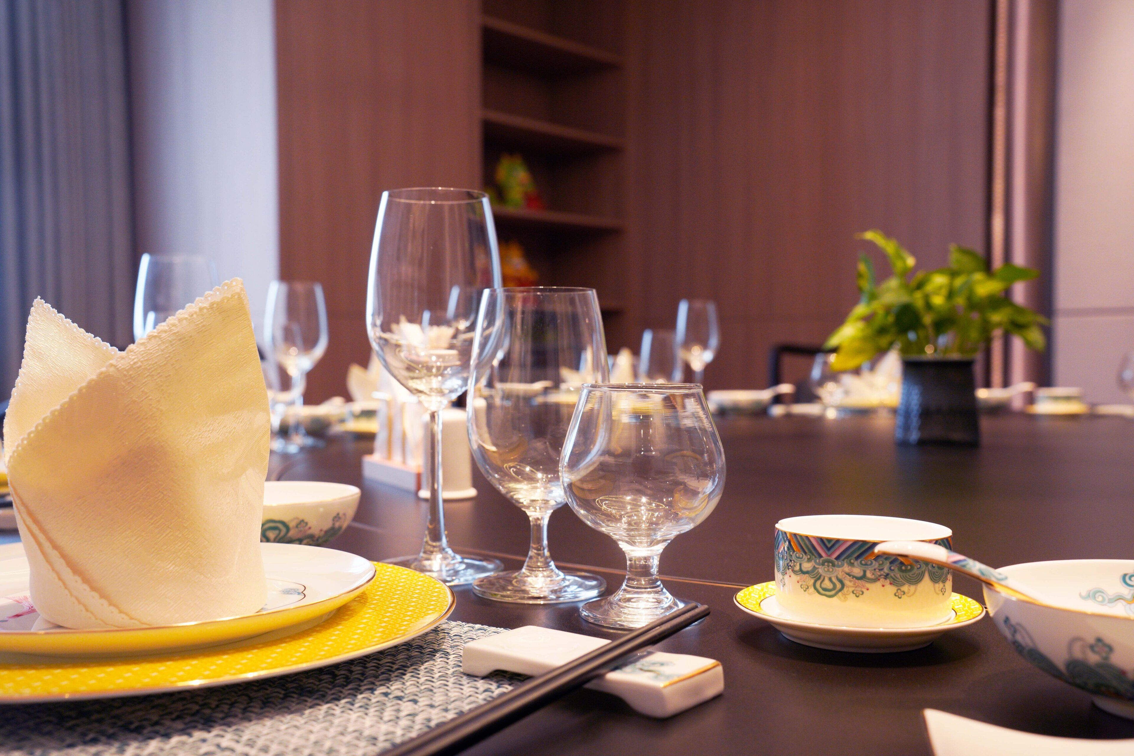 Una mesa de comedor dispuesta con diferentes platos, vasos y una planta.