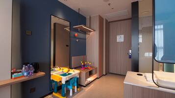 A modern hotel room with a large mirror, a small table with a chair, and a bed.