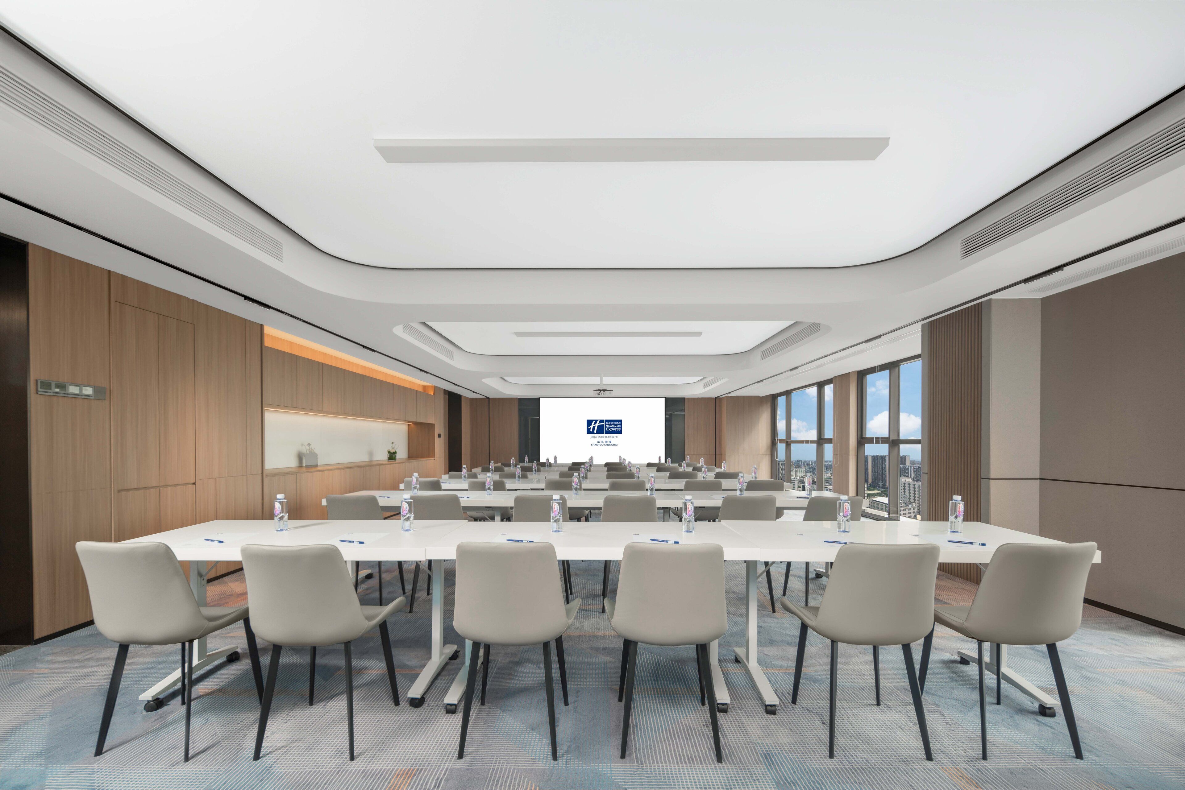 A conference room with a long table, multiple chairs, and a presentation screen.