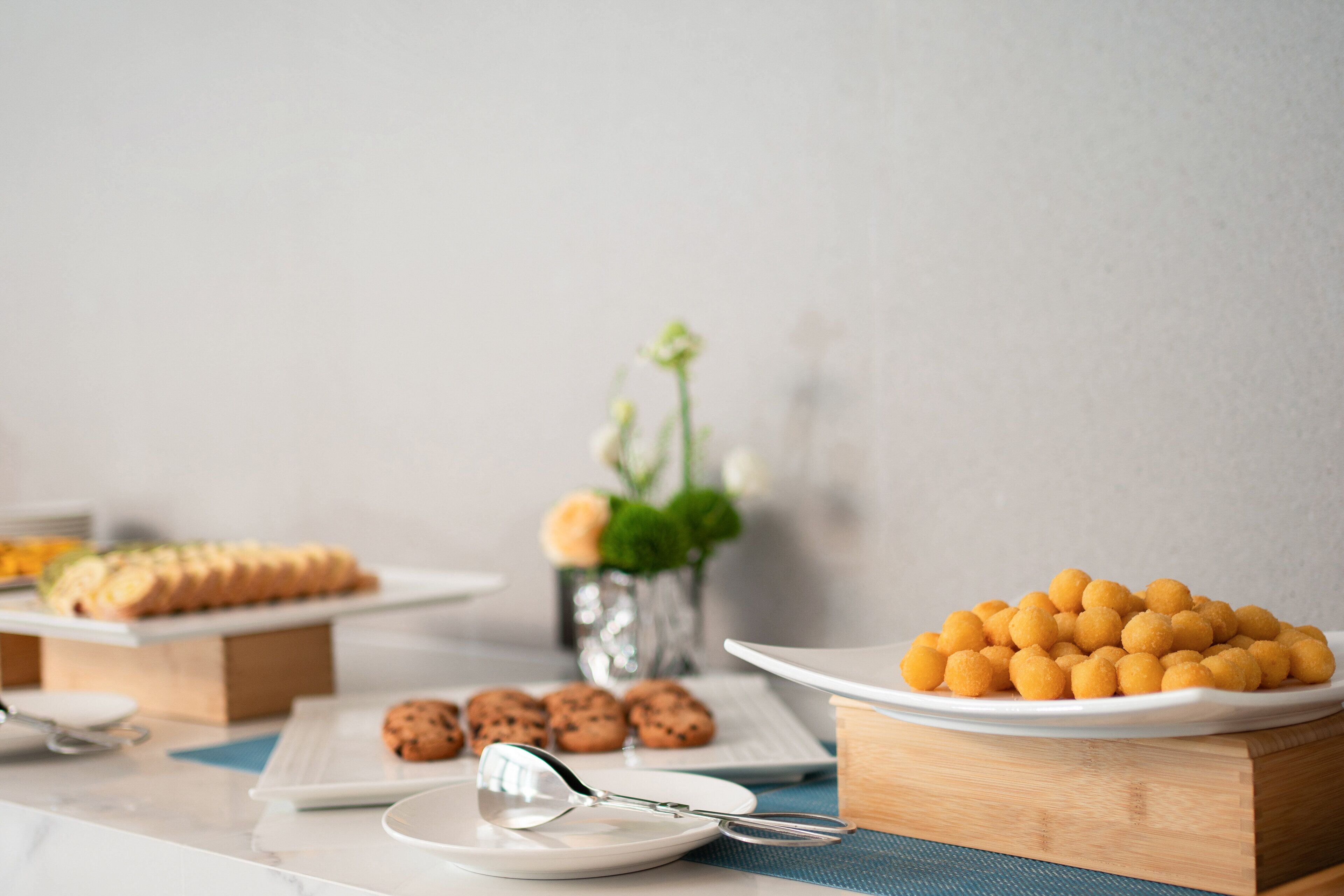 Una mesa de buffet con diferentes alimentos, incluyendo galletas y un plato de delicias redondas y doradas.