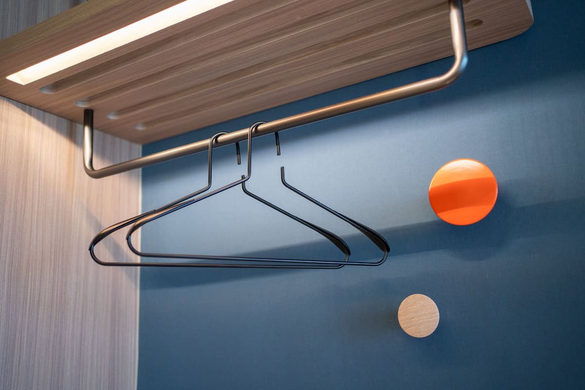 A metal hanger on a wall with a blue background and a wooden panel above it.