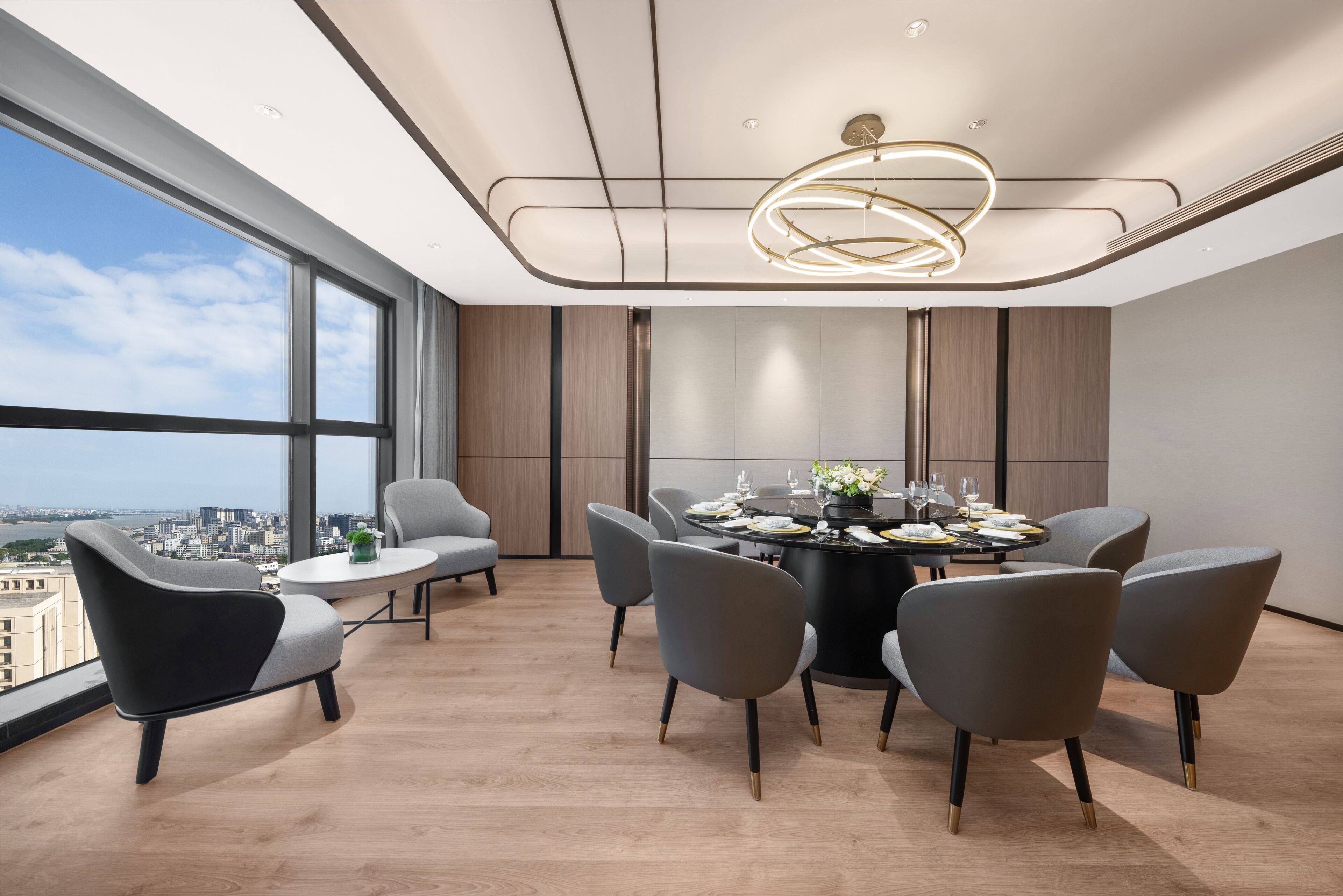 A modern conference room with a round table, six chairs, and a city view through large windows.