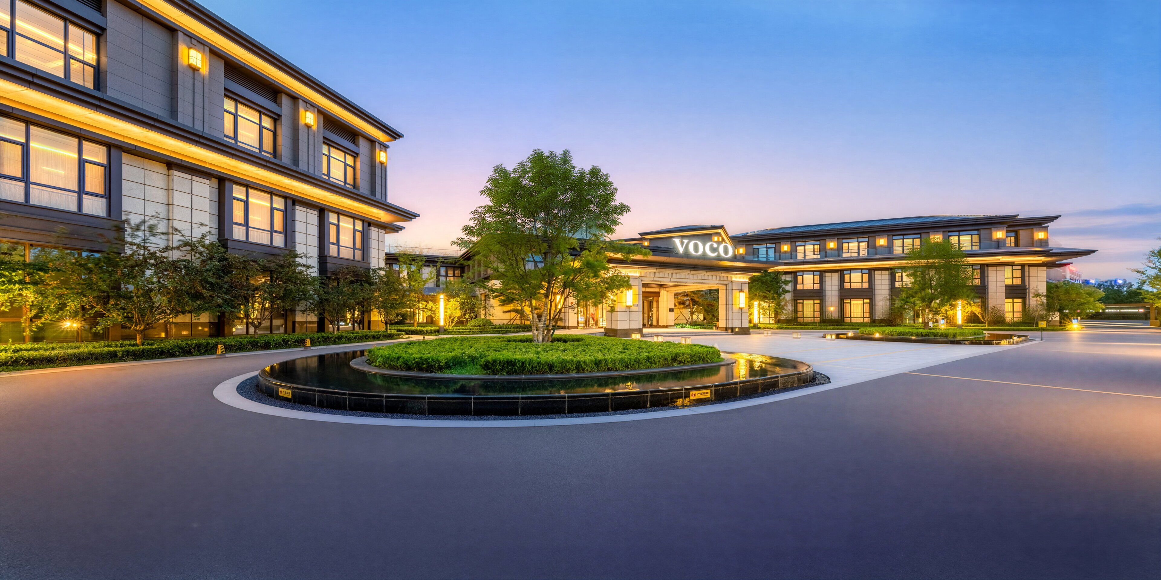 Un hôtel moderne doté d’une allée circulaire, d’un aménagement paysager bien entretenu et d’une entrée imposante.