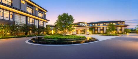 A modern hotel with a circular driveway, well-maintained landscaping, and a prominent entrance.