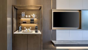 A modern kitchen with a built-in coffee station, a flat-screen TV, and a sleek countertop design. - voco Xiongan by IHG (Baoding)