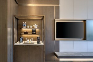 A modern kitchen with a built-in coffee station, a flat-screen TV, and a sleek countertop design.