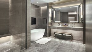 A modern bathroom with a freestanding bathtub, a bench, and a large mirror above the sink. - voco Xiongan by IHG (Baoding)