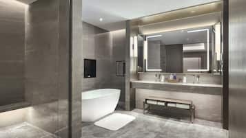 Un baño moderno con una bañera independiente, un banco y un espejo grande sobre el lavabo.