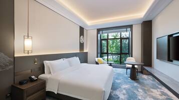 A hotel room with a large bed, bedside table, nightstand, and a TV mounted on the wall.