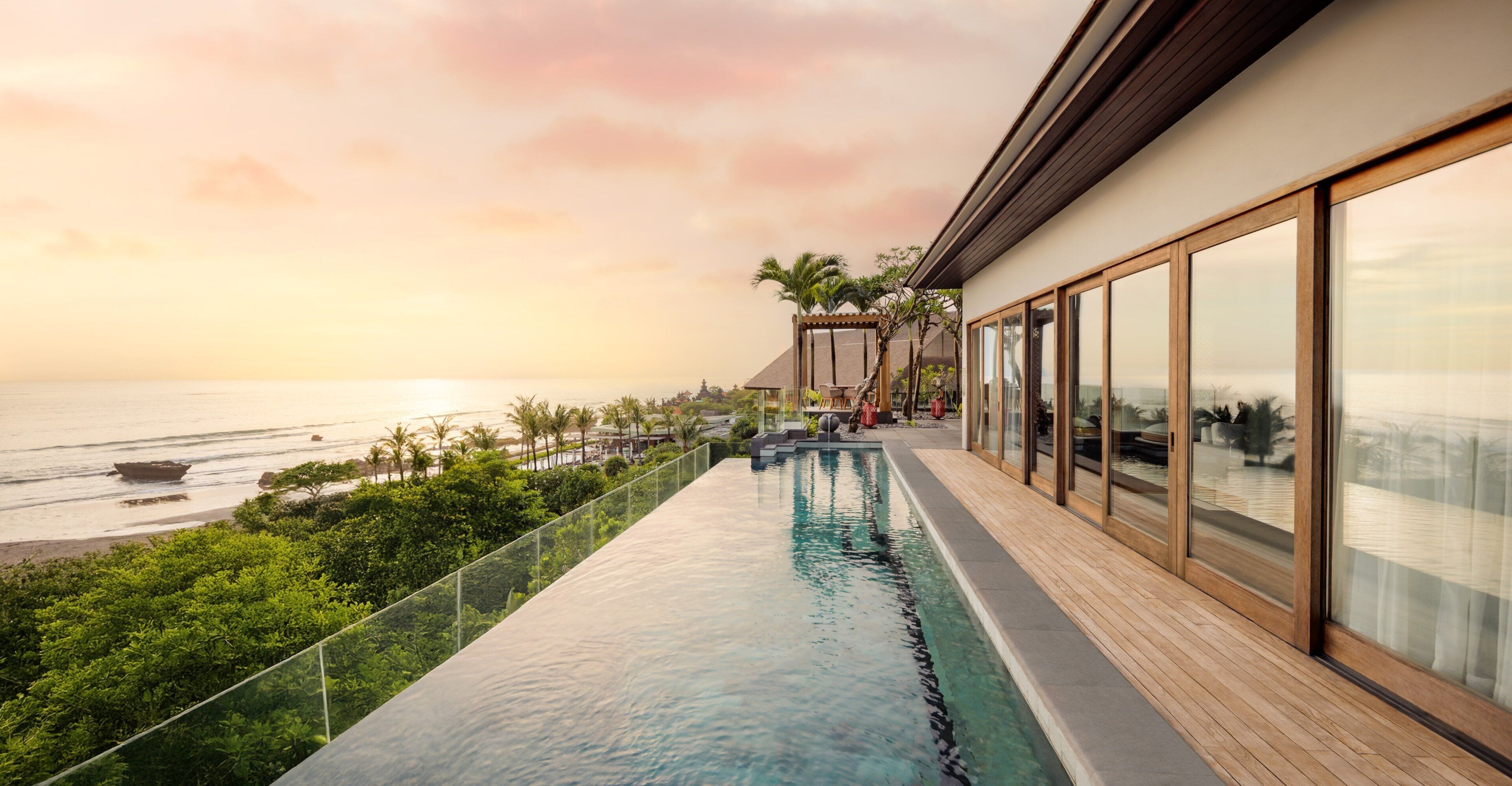 Una piscina infinita moderna con vista al océano y palmeras.