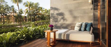 Ein moderner Außenbereich mit Holzterrasse, einer gepolsterten Couch mit Kissen und einem Blumenstrauß.