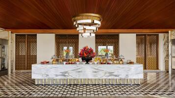 A spacious lobby with a marble reception desk, a modern chandelier, and traditional wooden screens.