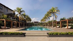 A pool area with lounge chairs and palm trees, surrounded by buildings.