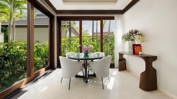 Un comedor con una mesa de vidrio y sillas, un jarrón con flores y un aparador de madera.