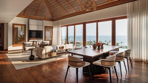 A spacious living room with a large wooden dining table, comfortable seating, and a view of the ocean. - Regent Bali Canggu (Canggu)