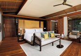 A modern hotel room with a large bed, a sofa, a small table, and a ceiling fan.