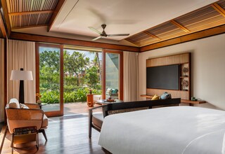A spacious bedroom with a large bed, a ceiling fan, and a TV on the wall.