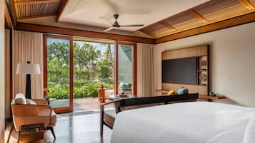 Un dormitorio amplio con una cama grande, un ventilador de techo y un televisor en la pared.