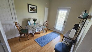 A dining area with a table, chairs, a vase with flowers, and a blue rug. - Phoenix Farms Vineyard (Edward)