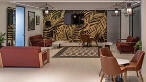 A modern lobby with red sofas, a patterned wall, and a flat-screen TV. - Portside Lodge Building (Marsaskala)