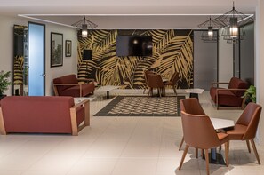 A modern lobby with red sofas, a patterned wall, and a flat-screen TV. - Portside Lodge Building (Marsaskala)