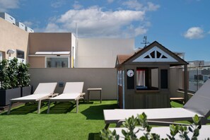 A rooftop lounge area with sun loungers, a small wooden structure, and a clear sky. - Portside Lodge Building (Marsaskala)