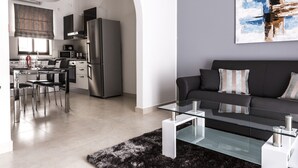 A modern living room with a black sofa, glass coffee table, and a black furry rug. - Portside Lodge Building (Marsaskala)