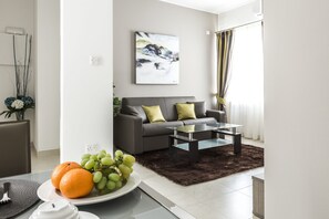 Un salon moderne avec un canapé gris, une table basse en verre et un tableau accroché au mur.