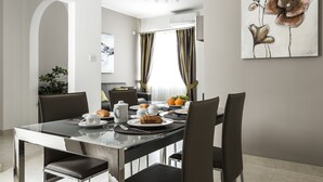 A modern dining area with a glass table, black chairs, and a painting on the wall. - Portside Lodge Building (Marsaskala)