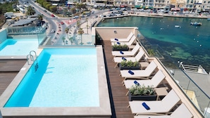 Una piscina al terrat amb gandules i vista al port esportiu.