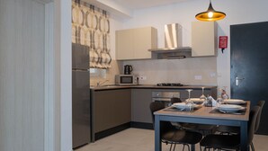 Cozinha moderna com área de jantar, equipada com micro-ondas, fogão e mesa de jantar para quatro pessoas.