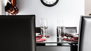 A dining table with two wine glasses and a water glass, set with red napkins and silverware. - Portside Lodge Building (Marsaskala)