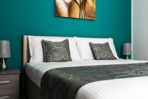 A hotel room with a bed, two nightstands, and a painting on the wall. - Portside Lodge Building (Marsaskala)