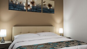 Una habitación de hotel con una cama, dos lámparas de noche, un cabecero y tres cuadros de flores colgados en la pared.