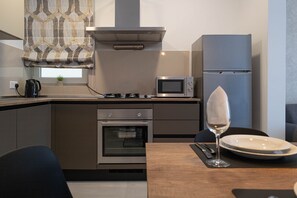 A modern kitchen with a built-in oven, microwave, and a stainless steel refrigerator.