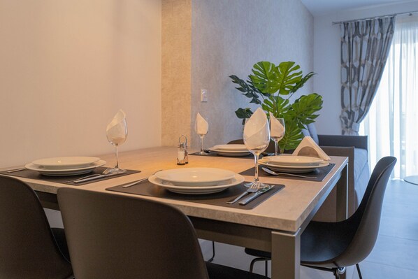 A dining table set for four with plates, glasses, and cutlery. - Portside Lodge Building (Marsaskala)