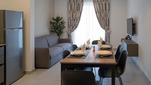 Et moderne køkken med spiseområde, sofa og fjernsyn ophængt på væggen.