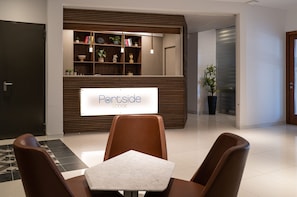 A reception area with a sign reading 'Rentside LODGE,' a reception desk, a seating area with chairs and a table, and a potted plant.