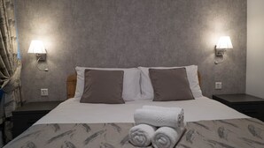 A hotel room with a bed, two nightstands, and two wall-mounted lamps. - Portside Lodge Building (Marsaskala)