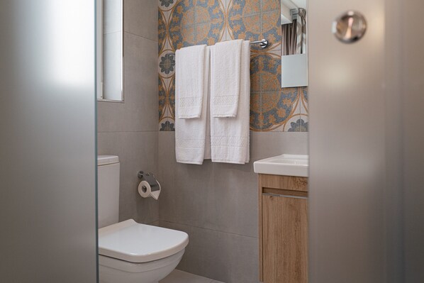 A bathroom with a toilet, a sink, and a mirror. There are two white towels hanging on a towel rack.