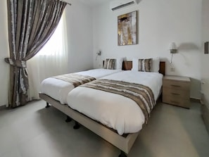 Ein Doppelbett mit einer gestreiften Decke, ein Nachttisch mit einer Lampe und ein Gemälde an der Wand.
